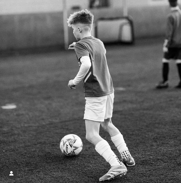 Young footballer Leo on the ball in Predator boots, black and white photo