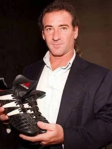 Craig Johnston holding a black adidas Predator boot